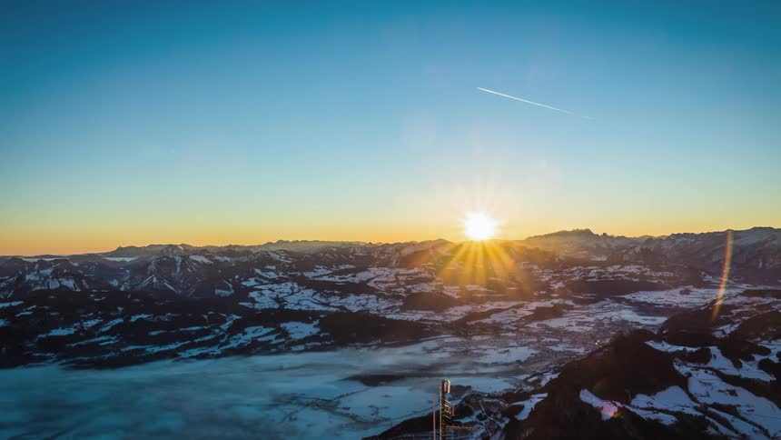 A city with mountains and the sun in the background