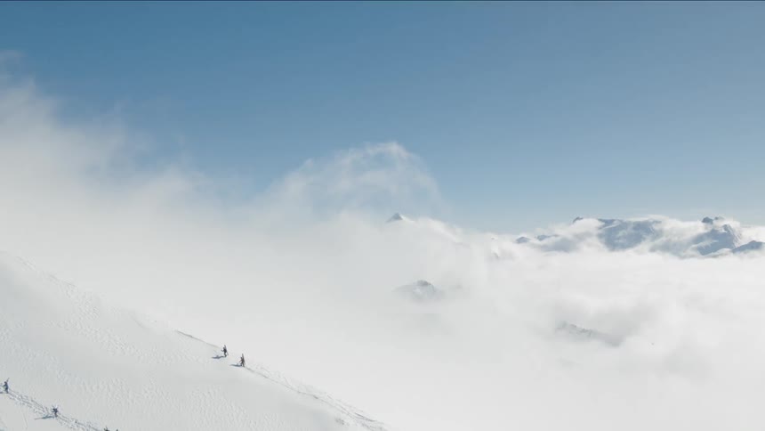 Four people on a snow covered mountain slope climbing up on a sunny day