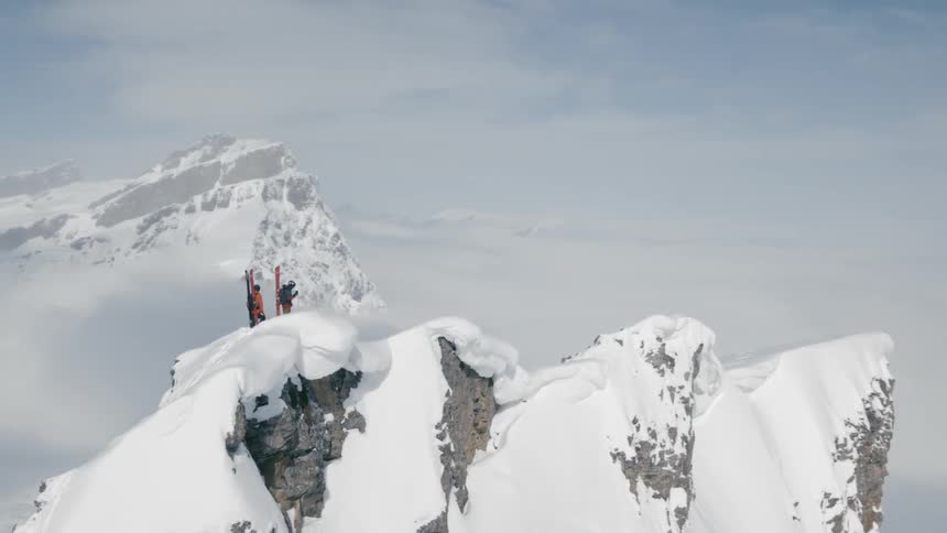 Two people stand on top of a huge snow covered mountain