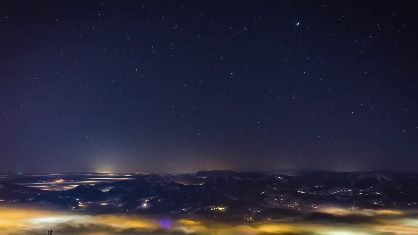 A large fog bank rolls over parts of a city at night
