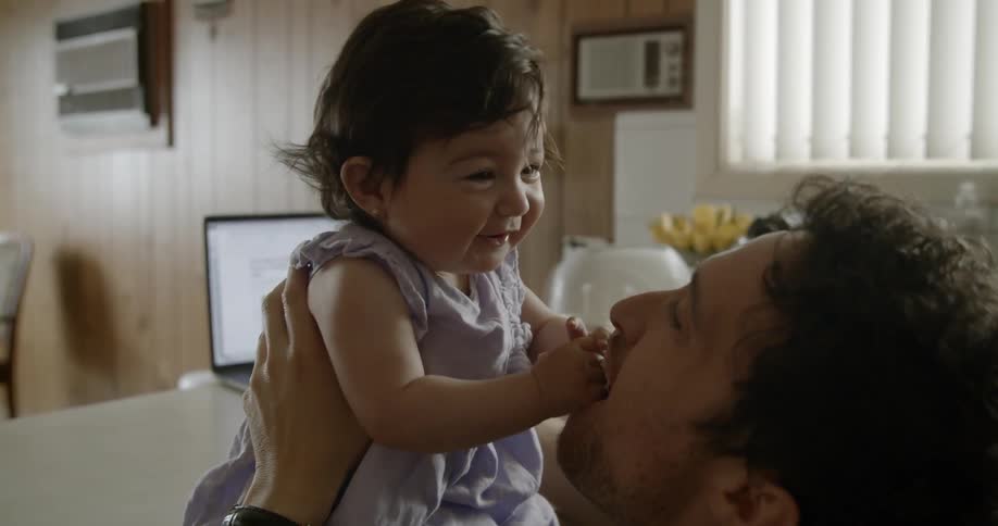 Young father holding and playing with his baby daughter