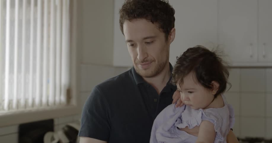 A man holds a baby girl and his cell phone