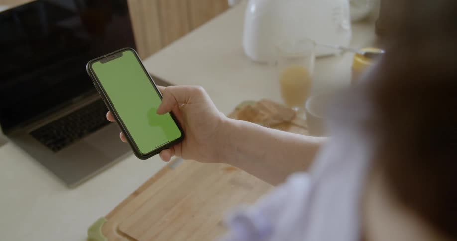Man uses smart phone in the kitchen during daylight