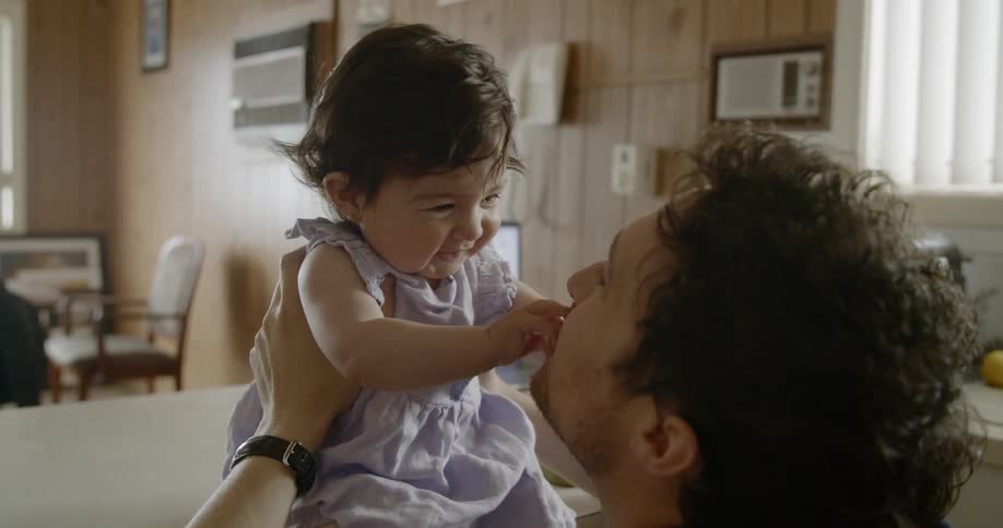 A man holding and playing with a baby female