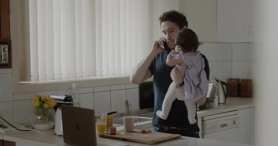 A man holding a baby talks on the phone