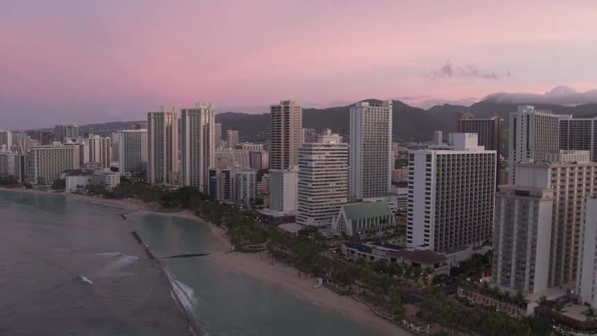 Skyline of the city with tall buildings next to the sea at dusk
