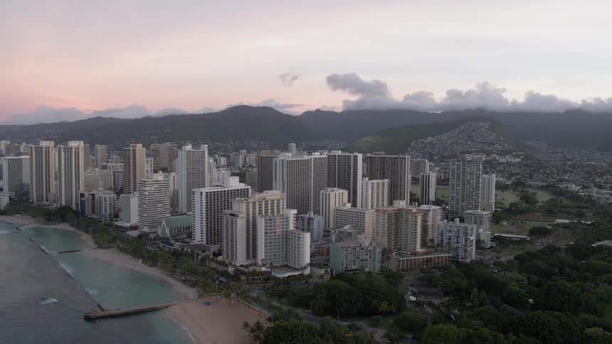 Skyline of the city with tall buildings next to the sea at dusk