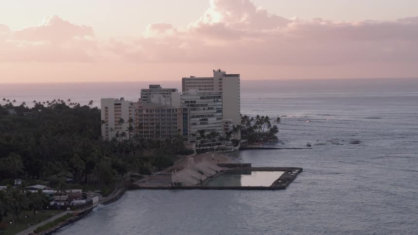 A large building sits on the coast surrounded by forest
