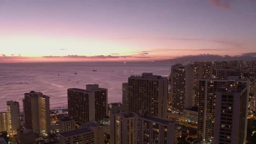 Skyline of the illuminated city at sunset next to the ocean