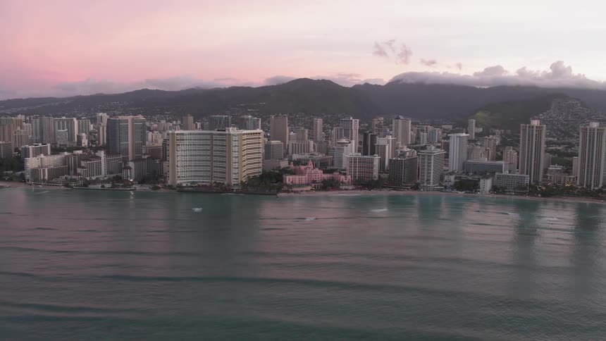Skyline of the city with tall buildings next to the ocean at dusk