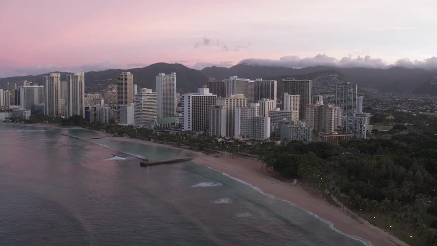 Skyline of the city with tall buildings next to the ocean at sunset