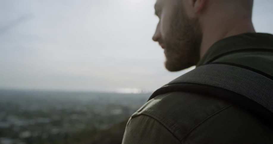 A caucasian man looking out over the landscape from a hill