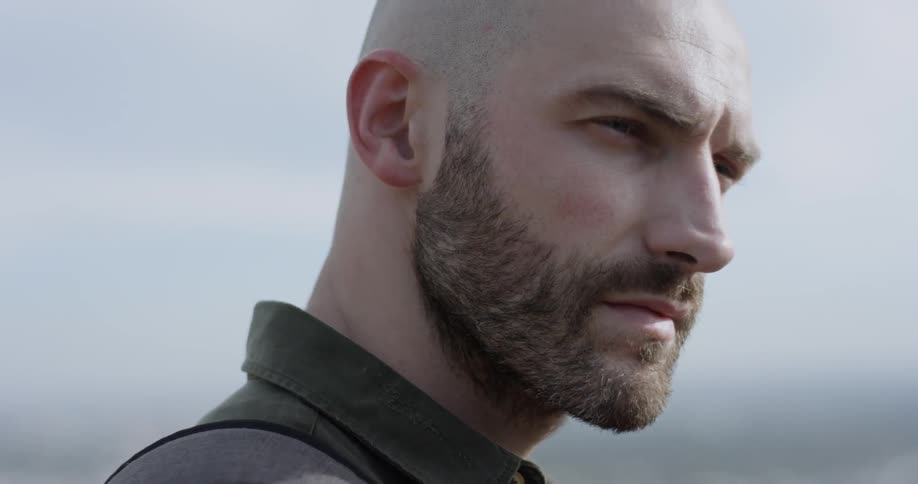 Bald bearded man looks around during daylight