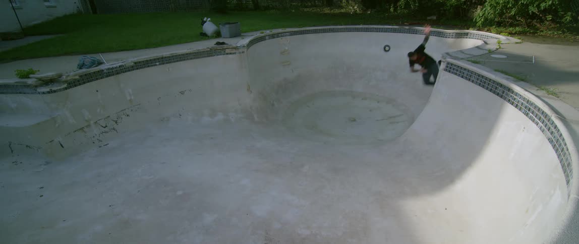 A man riding a skateboard in an empty swimming pool