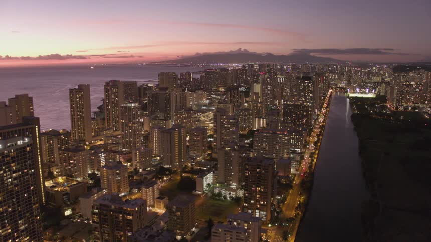 Skyline of the big illuminated city which is next to the sea at sunset