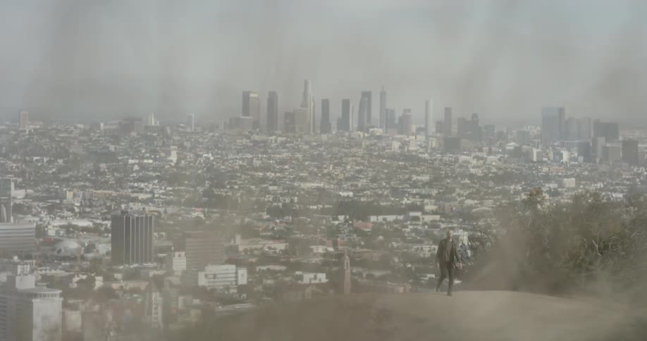 Man walks up hill away from sprawling city