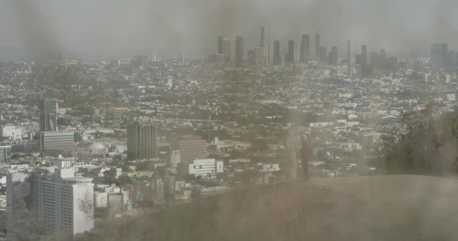 Man walks on top of a hill that overlooks a city