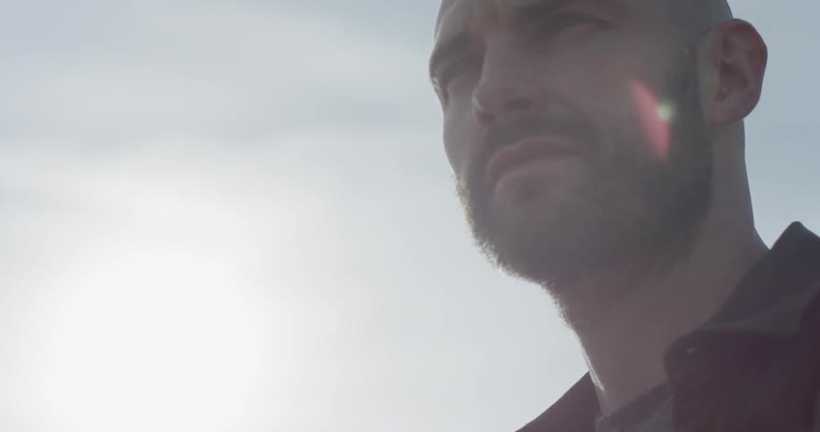 Bald bearded man looks around on a cloudy day