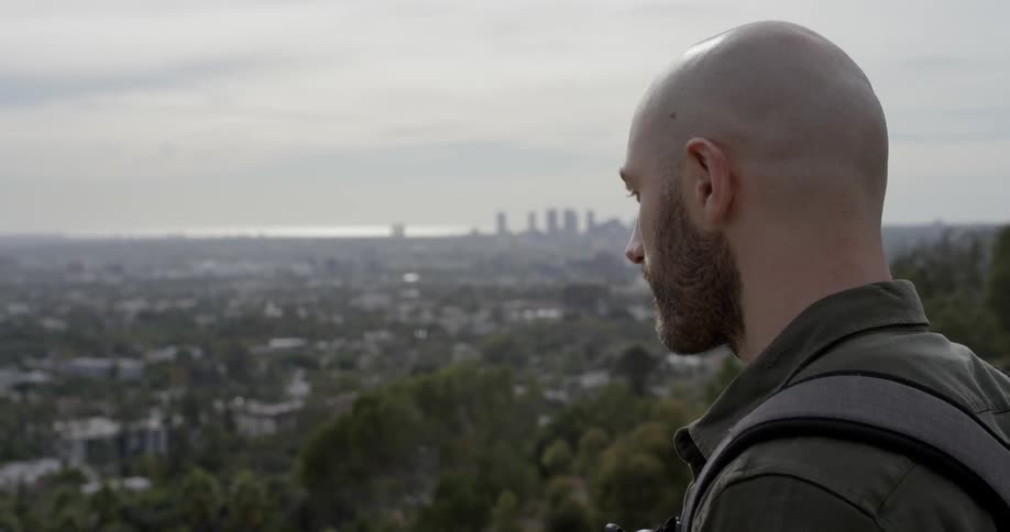 Man stands on a hill and looks at the city below