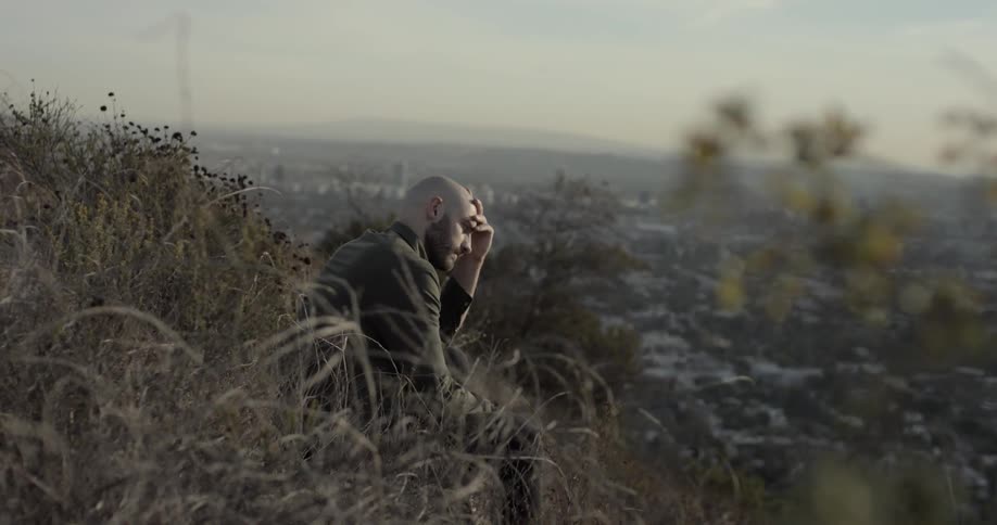 A man sitting on a cliff with the city in the background