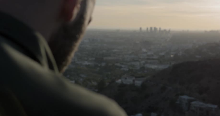 A man looks down on a dense neighborhood below his vantage point