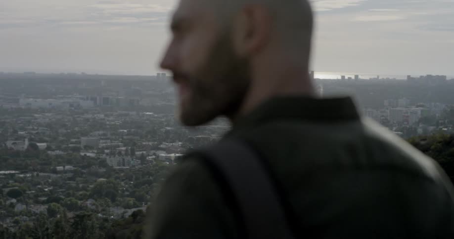 A man standing on a cliff with the city in the background