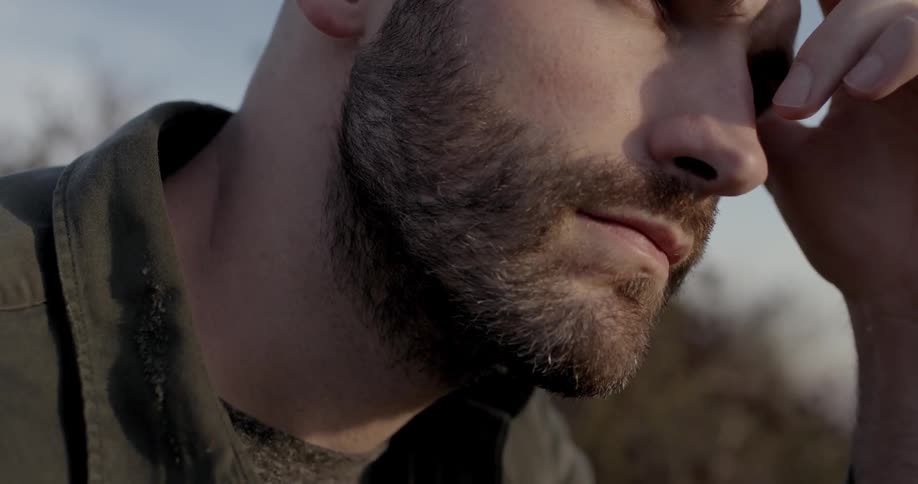 Bearded man sitting outdoors looking at horizon
