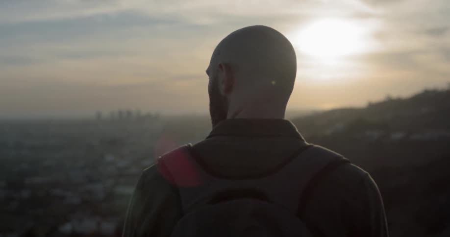 Man stands on a hill and looks at the city below