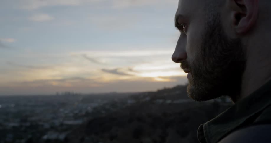 A man turns his head and looks over the city below him