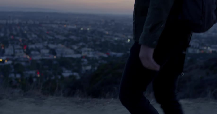 A person walking along a cliff overlooking a city