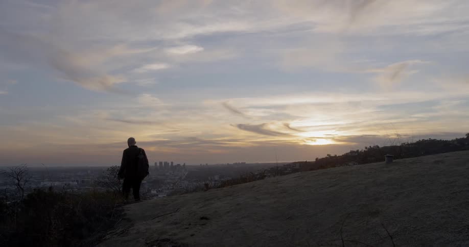 Silhouette of a man hiking down a trail at sunset