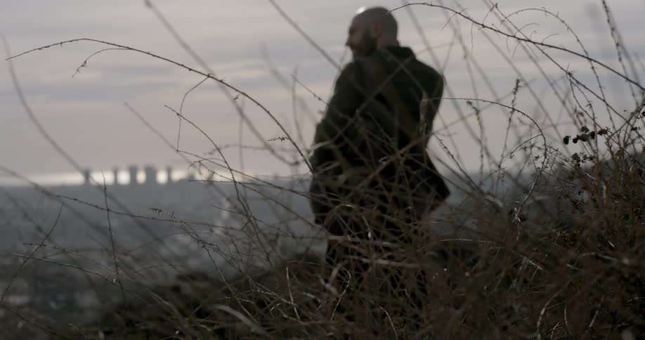 A man stands at the top of a hill