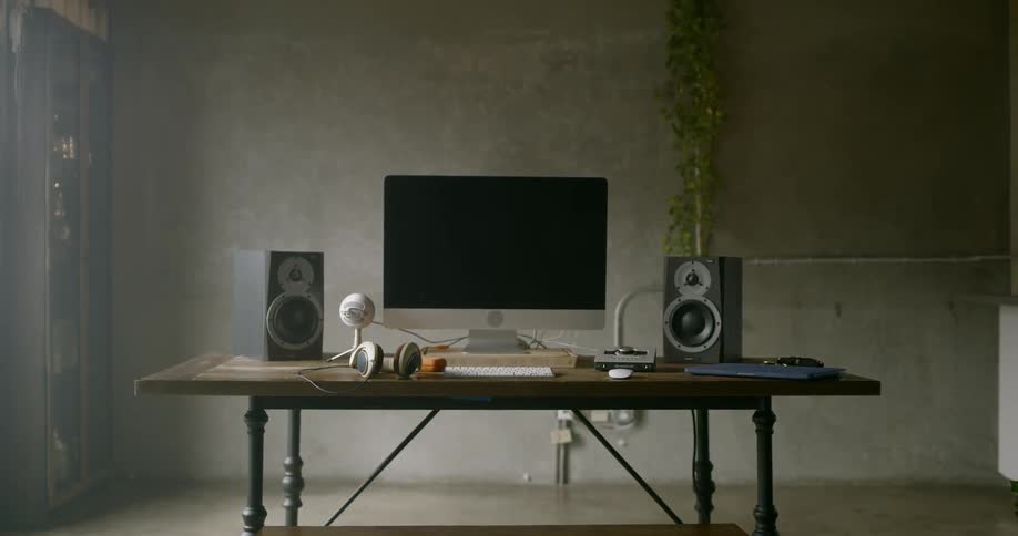 View of apple computer speakers headphones keyboard and mouse on the desk inside the room during daylight