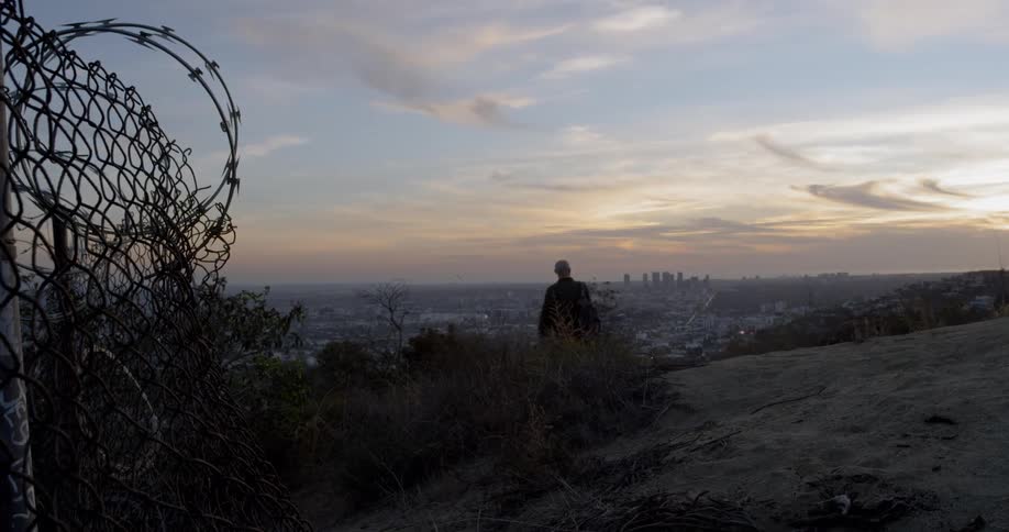 Silhouette of a hiker walking down a mountain trail overlooking the city