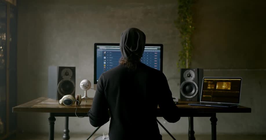 A white man works on a laptop and a desktop computer
