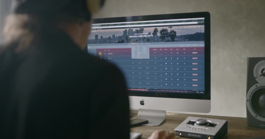 A white man works on a laptop and desktop computer