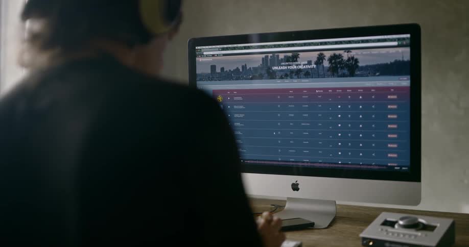 Man wearing headphones uses computer in a room during daylight
