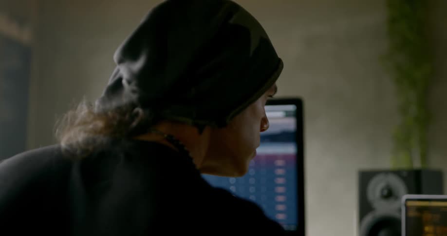 A man nods his head while sitting in front of multiple computer screens