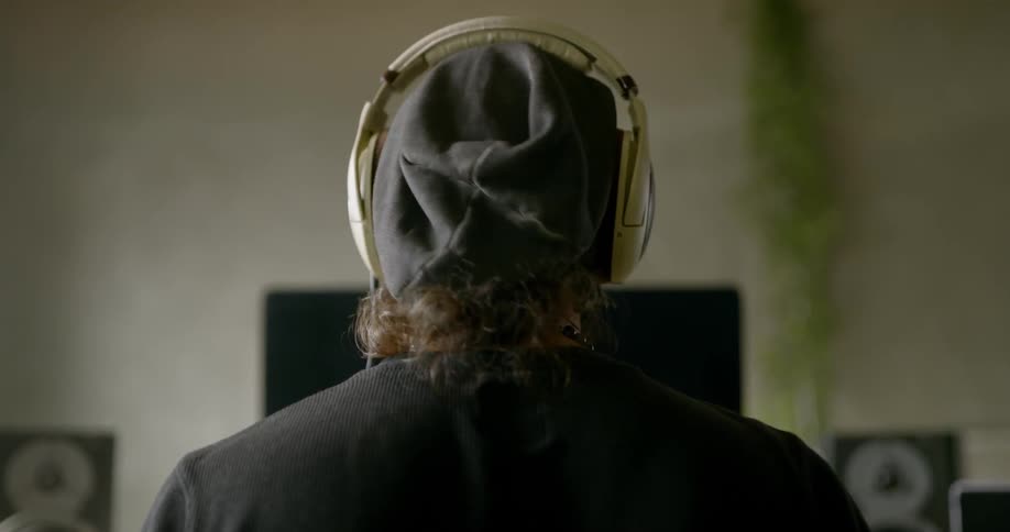 Man in black shirt places headphones on his head and bops his head up and down to what he hears