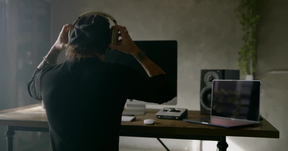 A man wears headphones while working on a computer at a desk