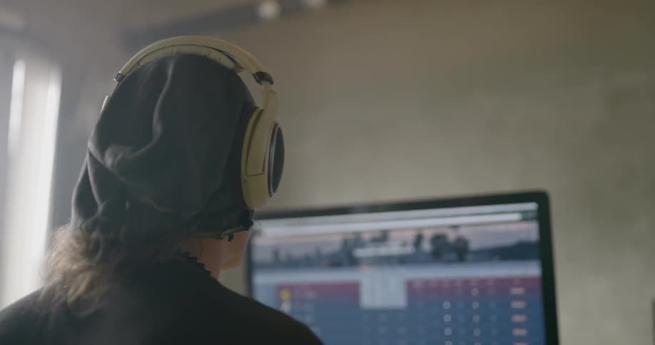 A man wearing headphones uses the computer on a large desk