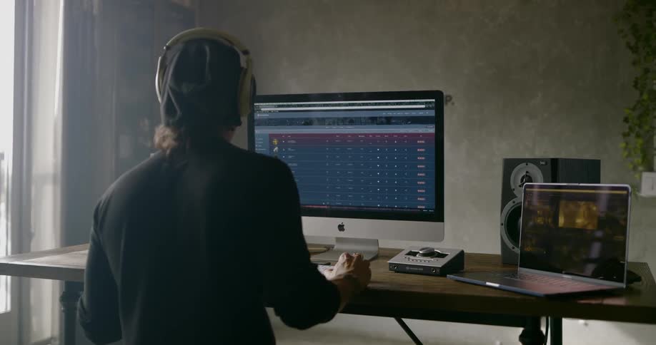 A man nods his head while working on a computer with headphones