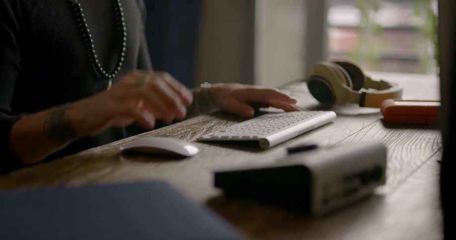 Woman sits at a desk as she works using a keyboard and mouse