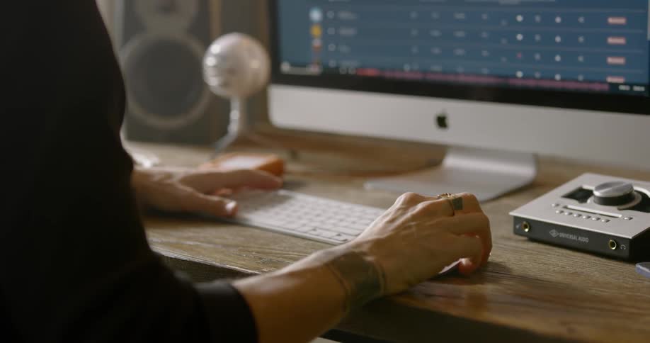 A man uses a computer and audio equipment while sitting at a table