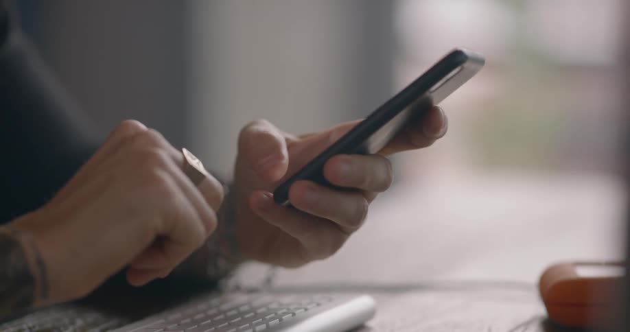 Woman sitting at the table uses smart phone during daylight