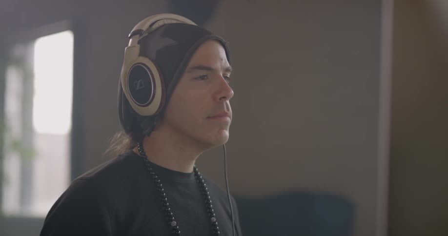 A man puts on headphones and looks to a computer