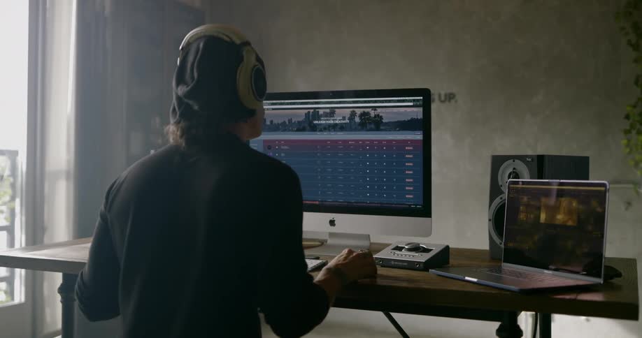 Man wearing black beanie and sitting at the table uses computer in a room during daylight