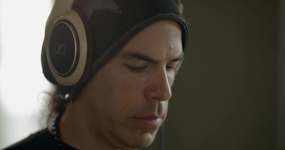 A man is wearing headphones while working at a computer in a room