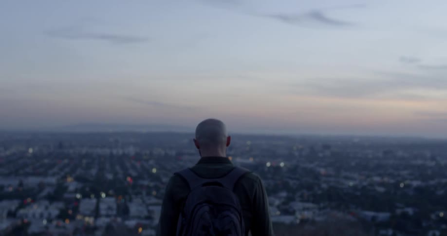 A person walks on a hill above a city