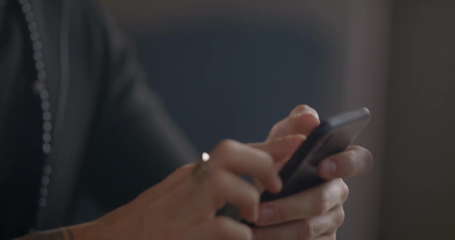 A caucasian man sitting at a desk using a smartphone